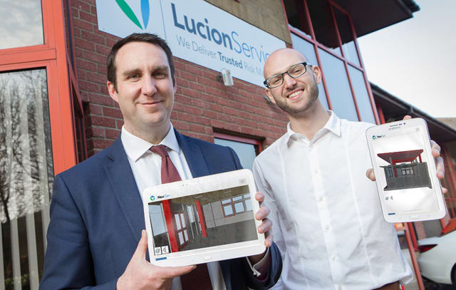 Lucion CEO Patrick Morton (left) with developer Alexei Holgate, who is partnering with the team to create an app that displays asbestos risk data. Both men are holding still images from their app. (Image courtesy of Lucion.)