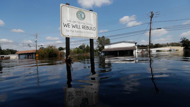 Infrastructure in the Carolinas took a beating after Hurricane Florence: in the town of Nichols, a sign celebrating rebuilding after Hurricane Matthew two years ago stands amidst the flooding. (Image courtesy of AP Photo/Gerald Herbert.)