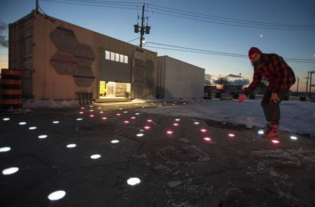 Sidewalk’s Jesse Shapins shows off the project’s new heated and lighted hexagonal pavement tiles, which are one of the innovations that the company hopes will make outdoor life in Toronto more pleasant during the winter. (Image courtesy of The Canadian Press/Tijana Martin.)
